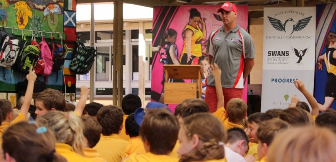 Swans representative gives a speech to kingegarten kids on a mat